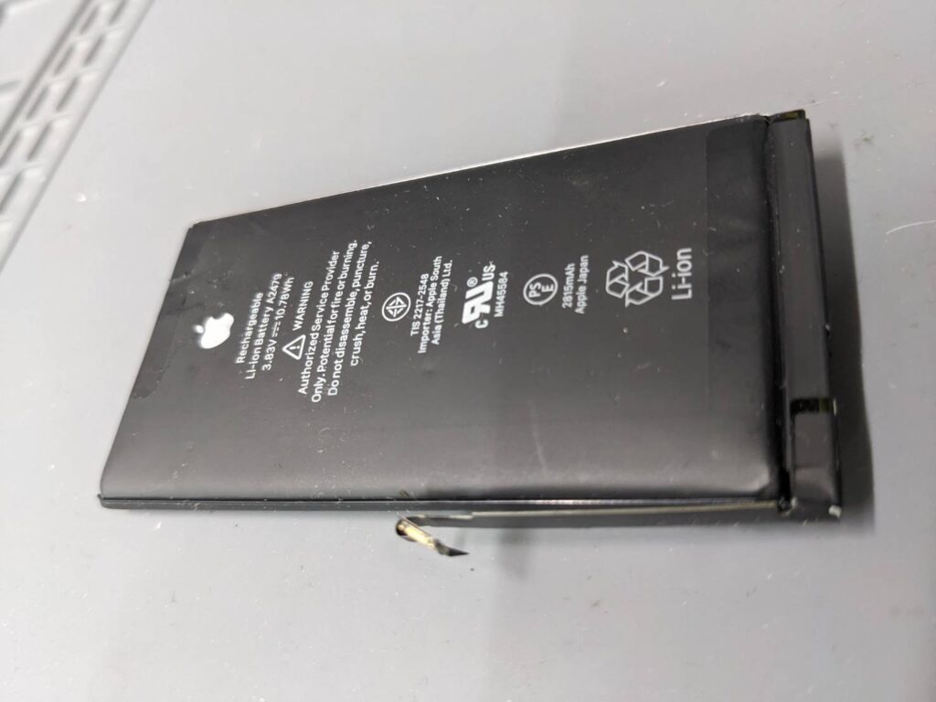 膨張して変形したiPhone12 Proの純正バッテリー。経年劣化により内部が膨らみ、交換が必要となった修理事例。