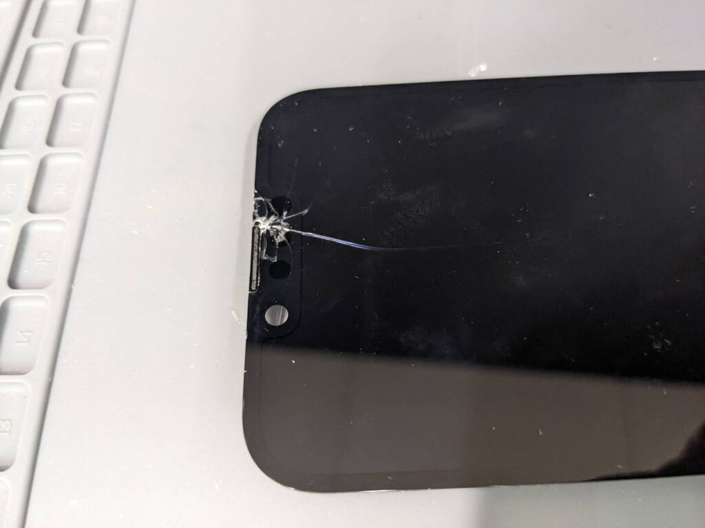 上部分が大きく破損したiPhone14のガラス割れを拡大した修理前の状態