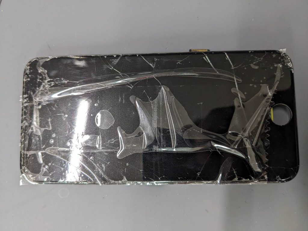 ガラスが広範囲に割れてテープで固定されたiPhone SE3のフロントパネル