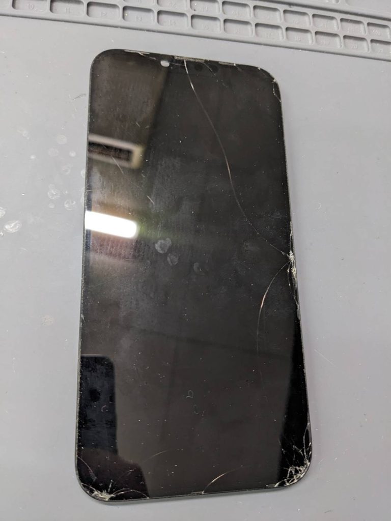 iPhone 13 Pro Maxの画面交換修理前の状態。画面の右側と下部を中心にガラスのひび割れが広がっている。