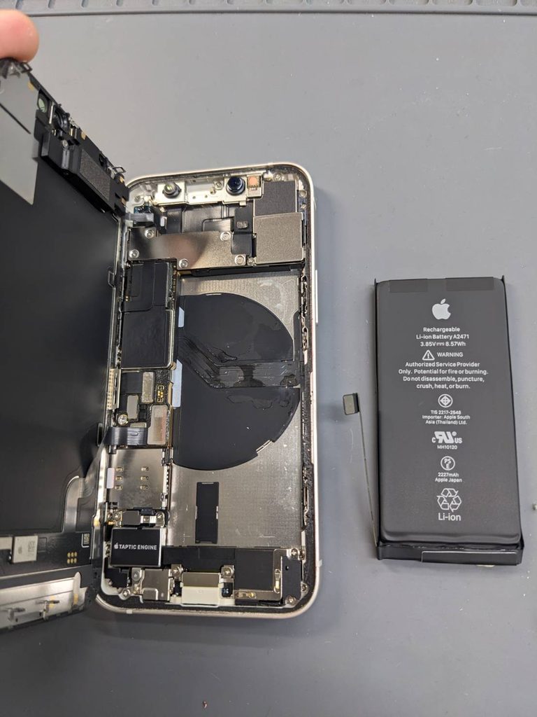 iPhone 12 miniのバッテリー交換修理。本体を開いて古いバッテリーを取り外し、内部の部品を確認している様子