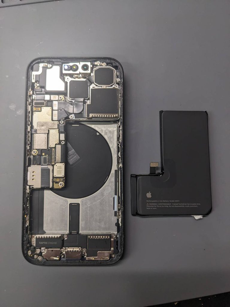 iPhone 15 Proのバッテリー交換修理で本体を分解し、内部と取り外したバッテリーを確認している様子