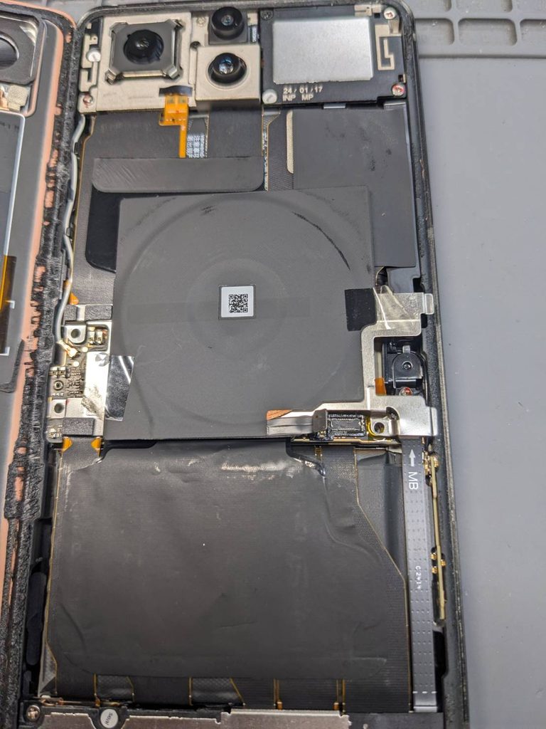 ZenFone 11 Ultraの基板入れ替え修理のために本体を分解した状態。内部のワイヤレス充電コイルやバッテリー、基板周辺の構造が確認できる様子。